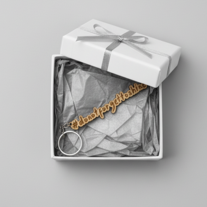 Wood keychain with '#dontforgettoshine' text in a gift box on a gray background