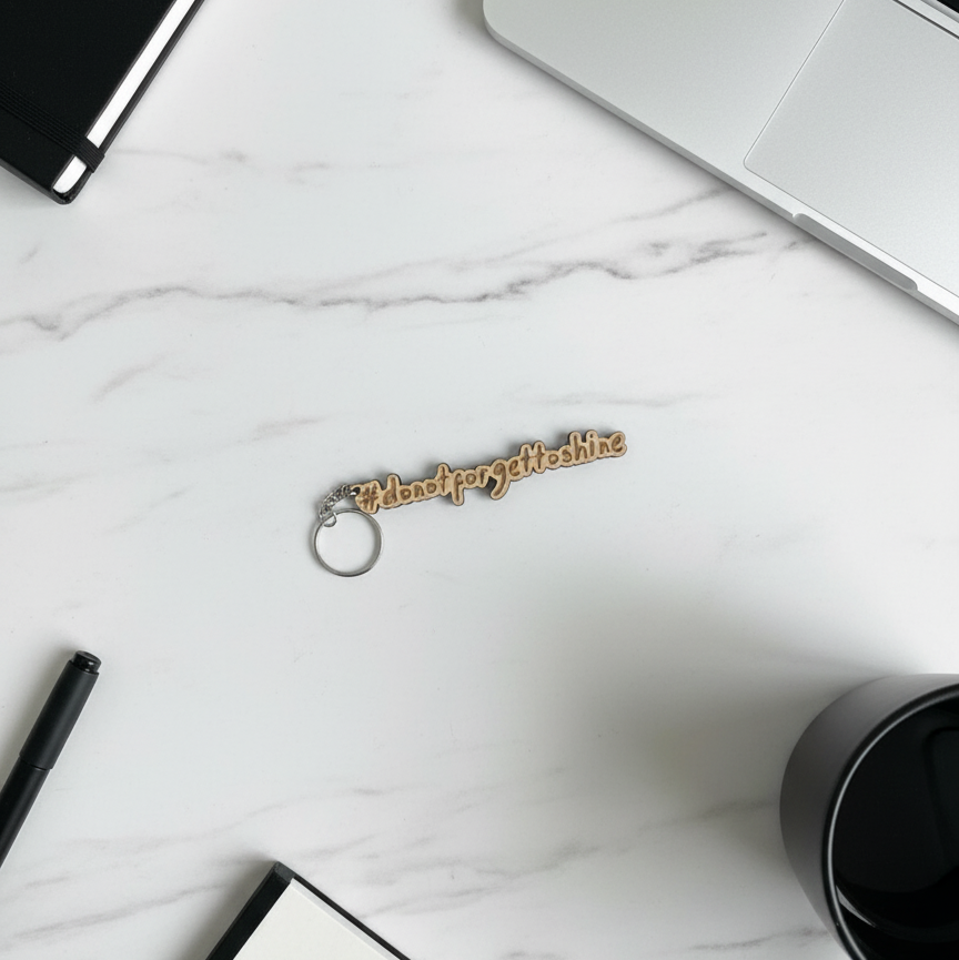 Wood Stargeizer keychain with text on a marble surface with a laptop, pen, and coffee cup.