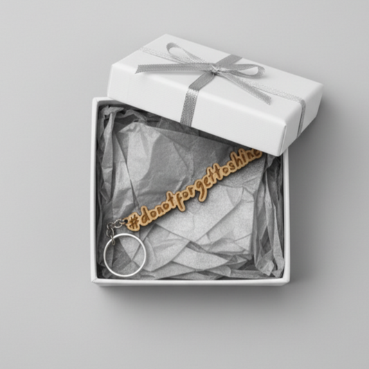 Wood keychain with '#dontforgettoshine' text in a gift box on a gray background