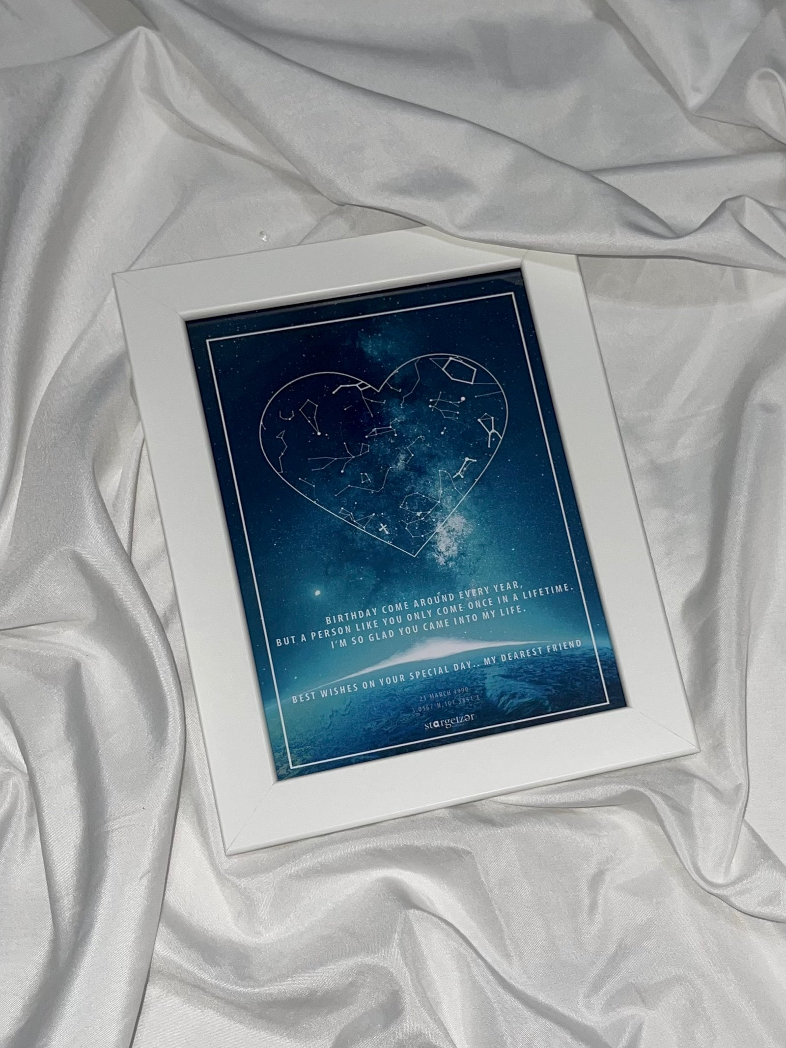 Framed star map with constellations arranged in a heart shape against a galaxy background, personalized message, styled on silky fabric.