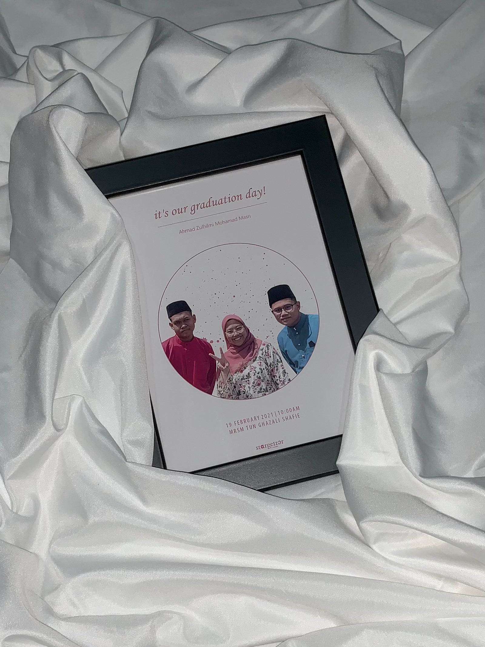 Framed custom star map with group graduation photo inside circular design, celebratory text, set on satin fabric.