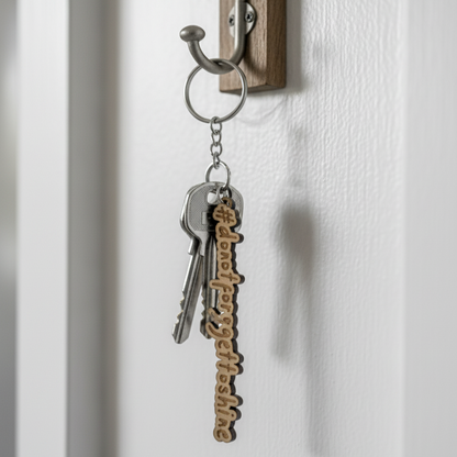 Stargeizer Wood Keychain with keys and a decorative tag hanging on a wooden hook against a white wall.