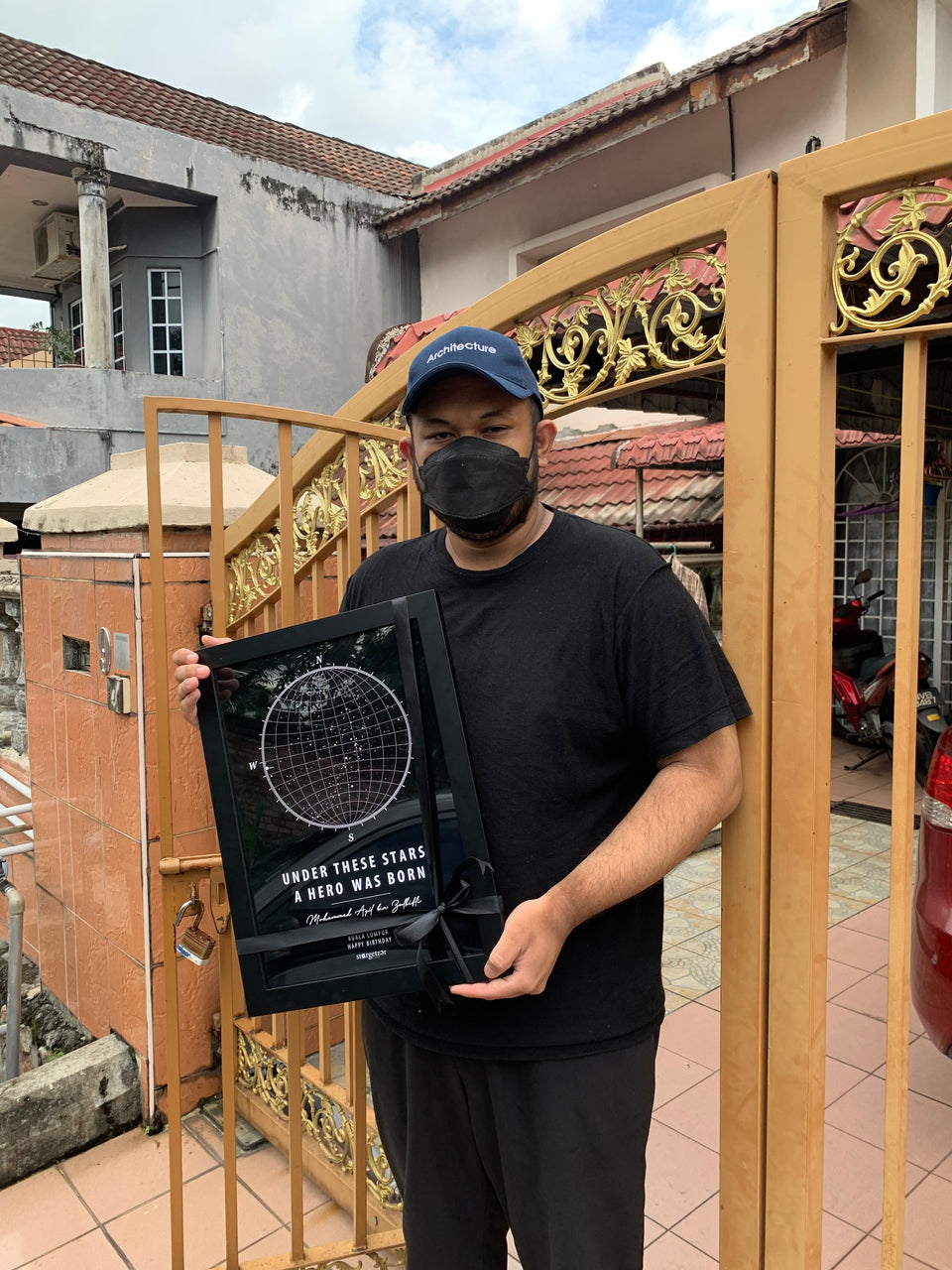 Man standing outdoors holding a A3 sized framed Stargeizer star map gift.