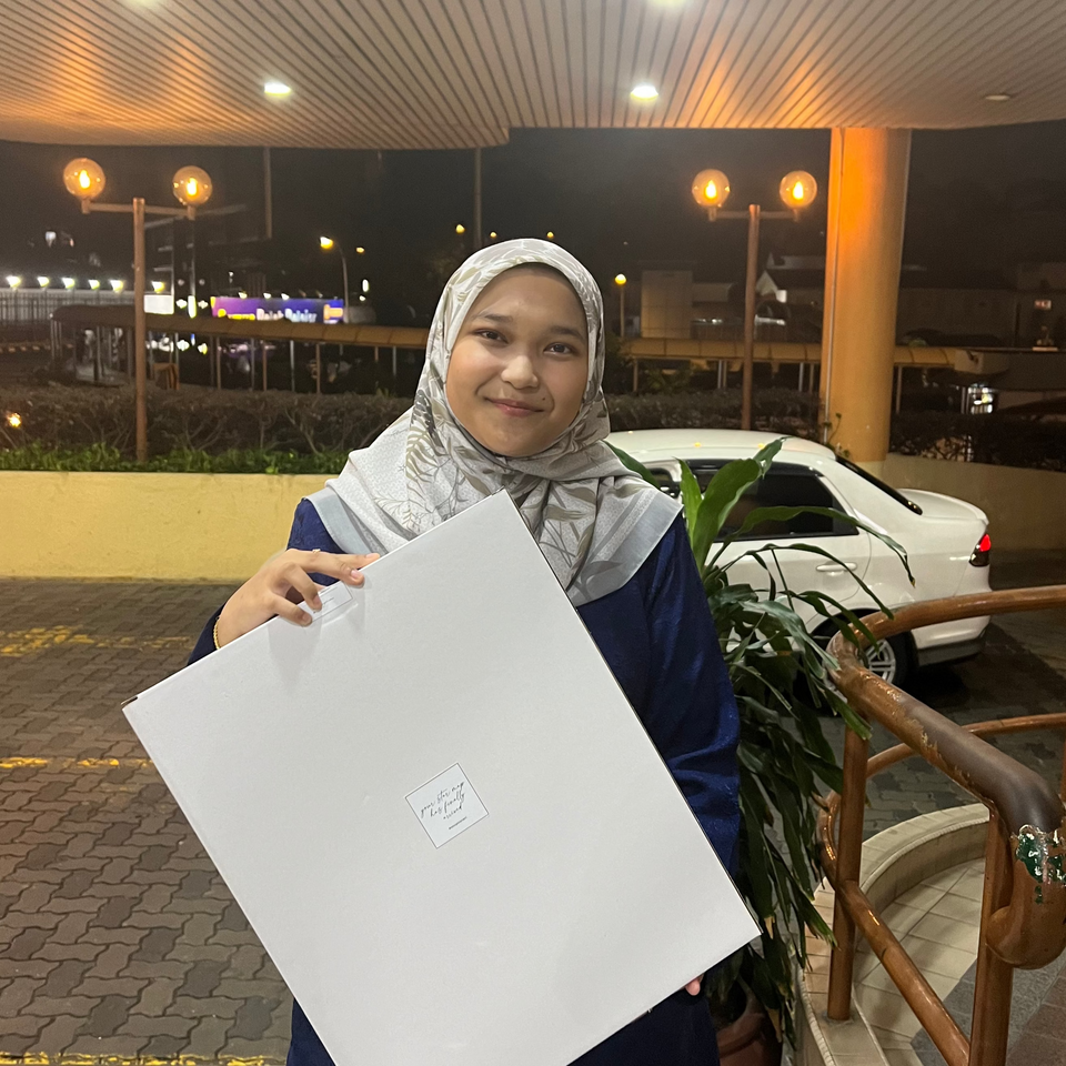 Woman standing outdoors at night holding a Stargeizer gift box, smiling at the camera.