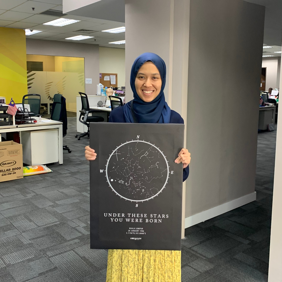 Smiling woman holding an A2 size Stargeizer star map poster inside an office.