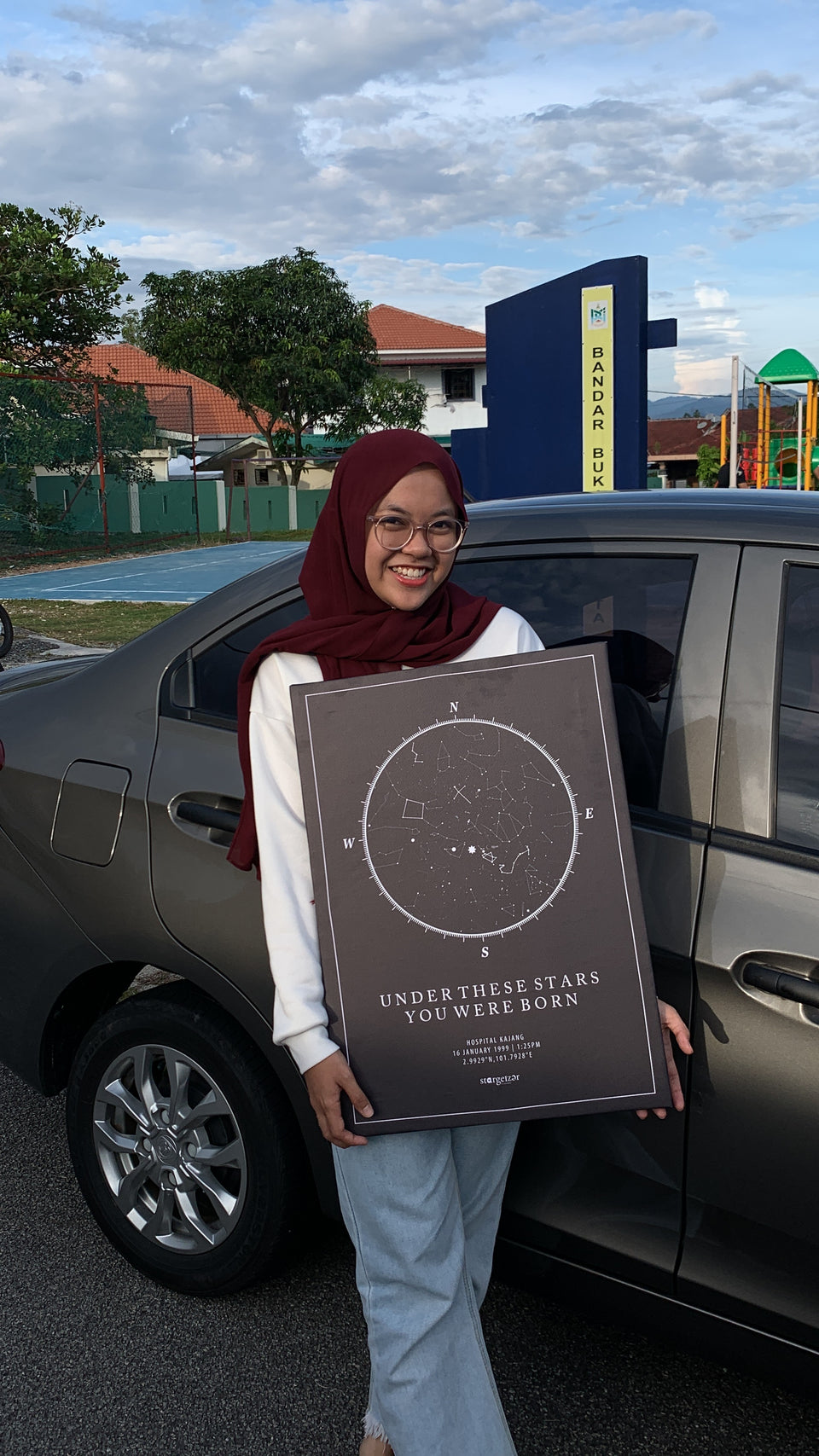 Woman standing outdoors holding an A2 size Stargeizer star map poster.